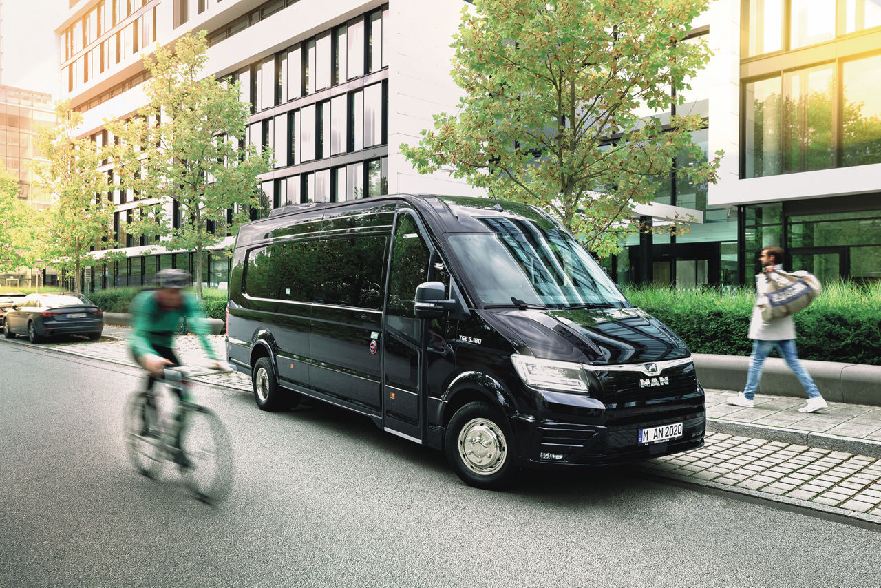 Black MAN TGE Combi Van parked in front of modern office buildings